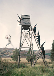 surreal men with cone hats climbing a tower. a man leaping from the tower